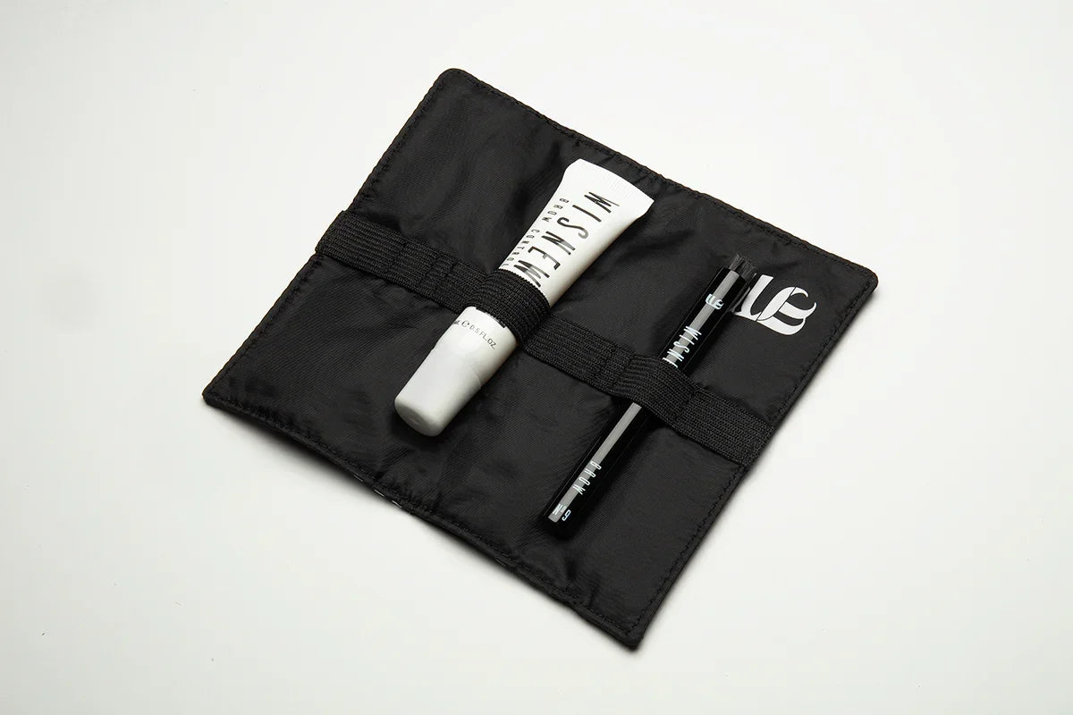 Inside view of the Wisnewski Complete Brow kit. Features the black inside of a magnetic pouch with an elastic band in the middle. The kit also contains a #9 Eyebrow Brush and a white tube of the Extra Strong Control Gel for eyebrows.